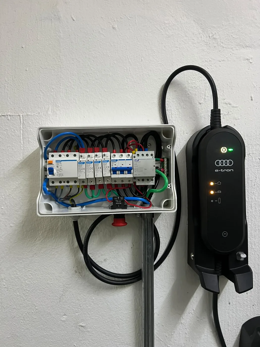 Quadro de um circuito de recarga: disjuntor dedicado, dispositivo DR e DPS, com o carregador ao lado